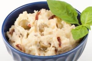 Mashed potatoes with olives and fresh basil in bowl