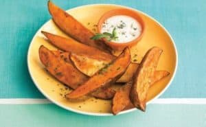 Plate of seasoned sweet potato wedges with dipping sauce