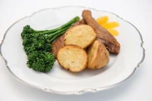 Plate with sausage, roasted potatoes, steamed broccolini, and sauce