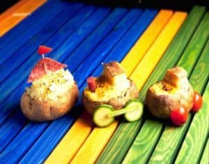 Creative stuffed potatoes shaped like toy vehicles on rainbow background