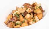 Roasted potato wedges with herbs in white bowl