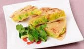 Plate of sliced stuffed flatbread with fresh herbs garnish