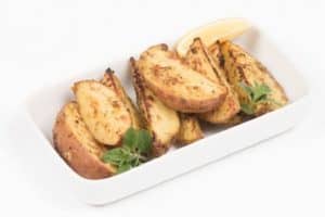 Roasted potato wedges garnished with parsley in white dish