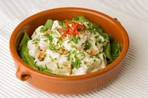 Creamy mushroom salad garnished with herbs and red chili.