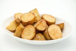 Bowl of roasted potato slices on white background