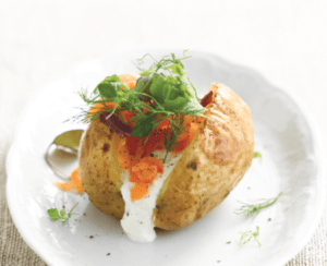 Baked potato with sour cream and fresh herbs garnish