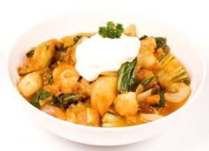 Gnocchi with spinach and sour cream in white bowl