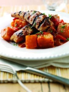 Grilled meat skewers with roasted vegetables on white plate