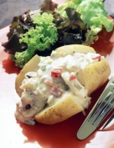 Baked potato with creamy vegetable sauce and fresh lettuce salad