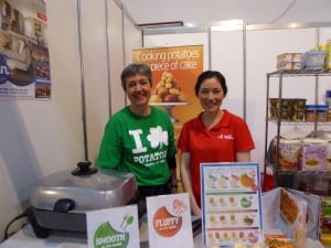Two people at potato cooking product booth with displays