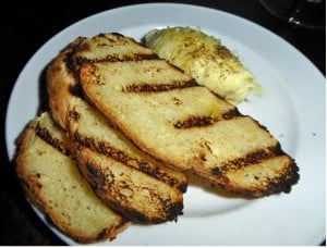 Grilled toasted bread slices served with seasoned butter on plate