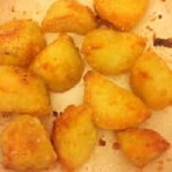 Golden crispy roasted potato wedges on a baking tray