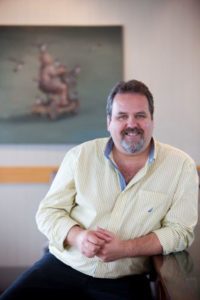 Smiling man in casual shirt sitting indoors near table