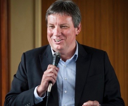 Man in suit speaking with microphone at event indoors