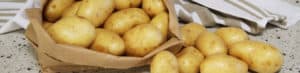 Fresh raw potatoes in paper bag on countertop