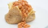 Baked beans spilling out of a sliced bread roll