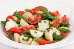 Fresh asparagus salad with tomatoes and turnips on plate