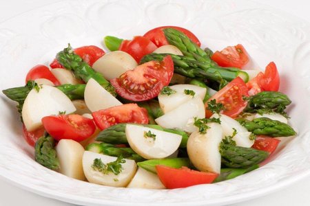 Fresh asparagus salad with tomatoes and turnips on plate