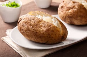 Baked potato with butter on white plate close-up