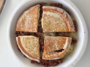 Sliced bread and diced meat in a white round dish