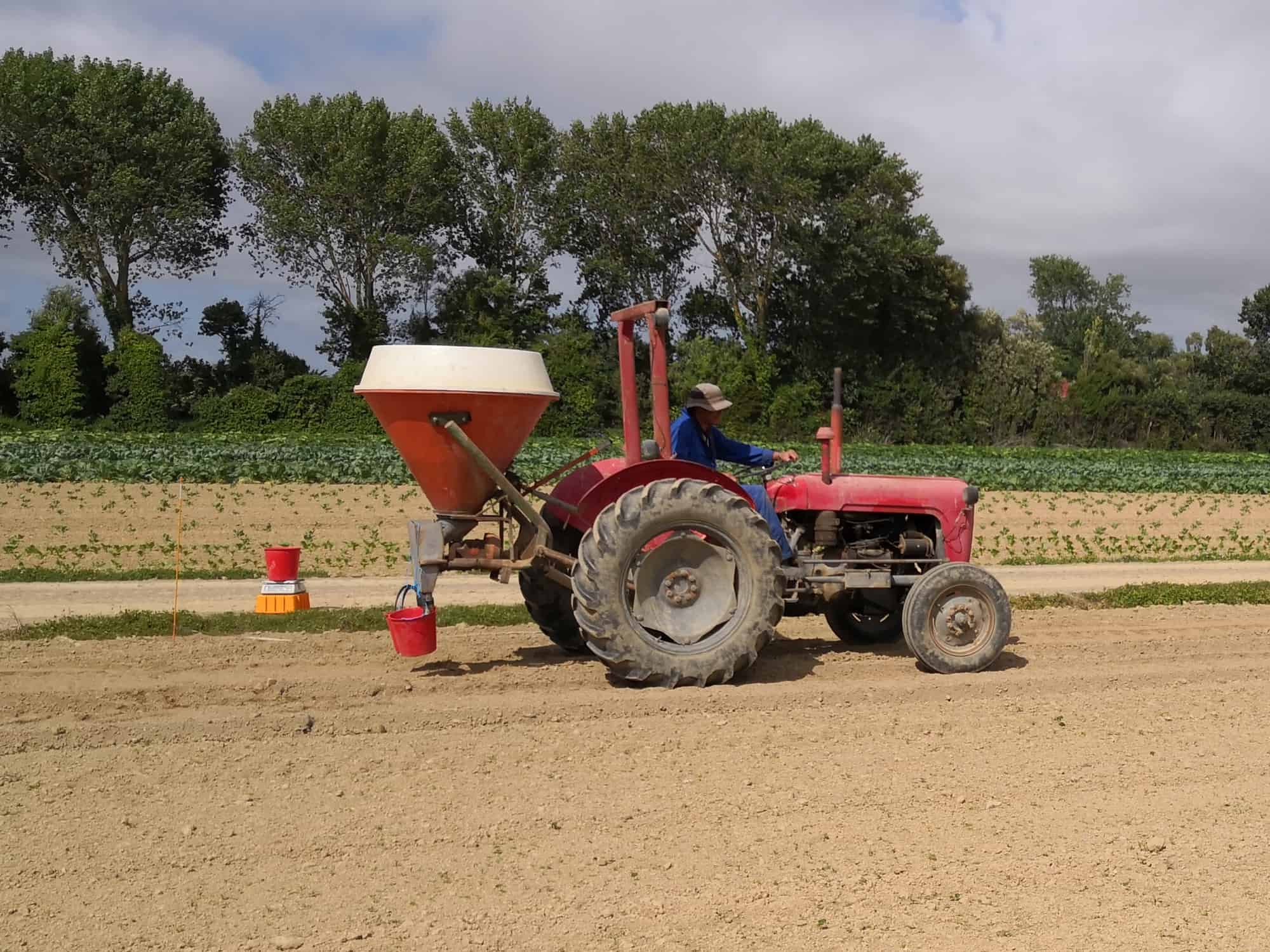 Red tractor with seed planter working on dry farm field