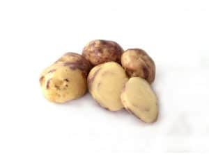 Purple and yellow potatoes with one cut in half on white background
