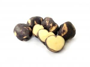 Purple and yellow striped oca tubers, whole and sliced.