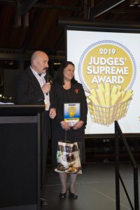 Two people accepting 2019 Judges' Supreme Award on stage