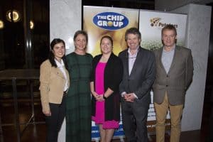Group of five professionals posing at The Chip Group event banner