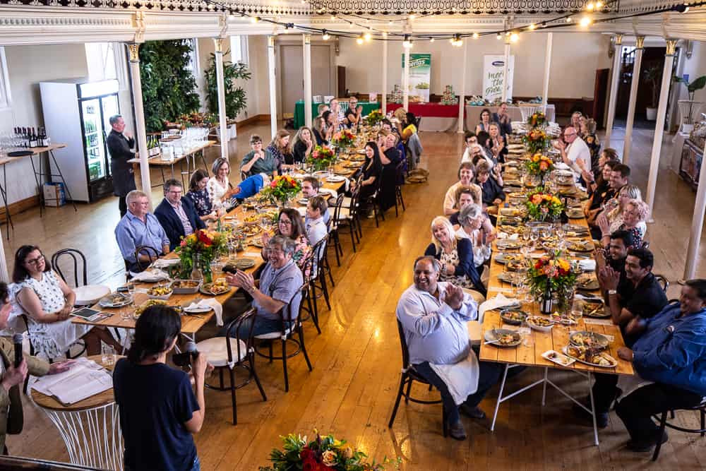 Large group enjoying meal at long decorated banquet table indoors