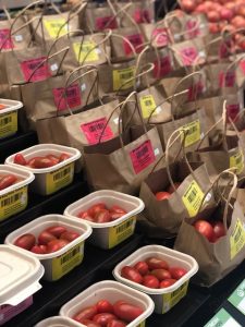 Containers and paper bags filled with fresh tomatoes at market