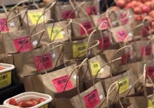 Rows of brown paper grocery bags with produce and labels