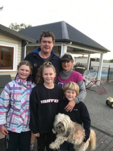 Family of five with small fluffy dog, outdoor porch background