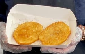 Two golden fried potato patties in white tray