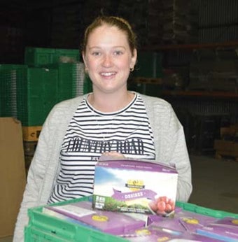 Woman smiling with boxes of fresh produce in warehouse