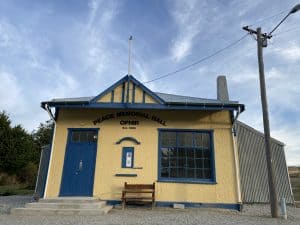 Yellow Peace Memorial Hall building with blue trim and door