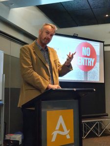 Man giving presentation pointing at "No Entry" sign on projector screen
