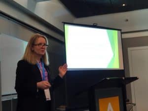 Woman giving presentation with projector screen and podium indoors