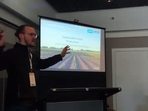 Man giving presentation on sustainable food production with projector screen.