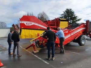 Men examining large red Grimme EVO 290 agricultural machinery outdoors