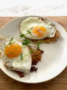 Fried eggs on crispy hash browns with fresh herbs.
