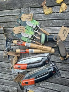 Assorted garden tools including pruners, saws, and a spray gun on bench