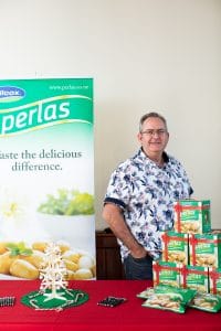 Man standing by Perlas brand potatoes display with promotional banner
