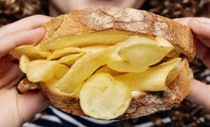 Close-up of sandwich filled with potato chips being held