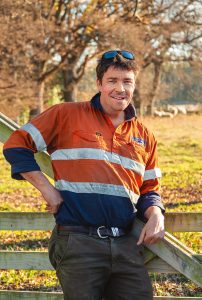 Smiling man wearing orange shirt and sunglasses outdoors