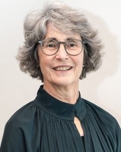 Older woman with gray hair and glasses smiling warmly