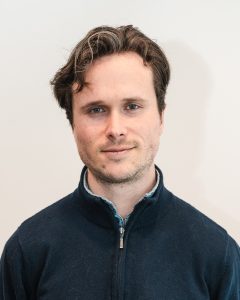 Portrait of a smiling man wearing a dark zip-up sweater