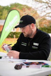 Man in Horticentre cap and jacket inspecting plant sample outdoors