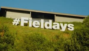 Large white hashtag Fieldays sign on grassy hillside outside building