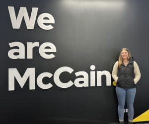 Woman standing next to "We are McCain" black wall sign